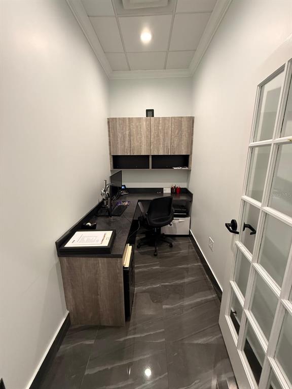 A small home office features a built-in desk, overhead cabinets, and dark tile flooring — 7901 KINGSPOINTE PARKWAY UNIT 19 # Office 4, ORLANDO, FL