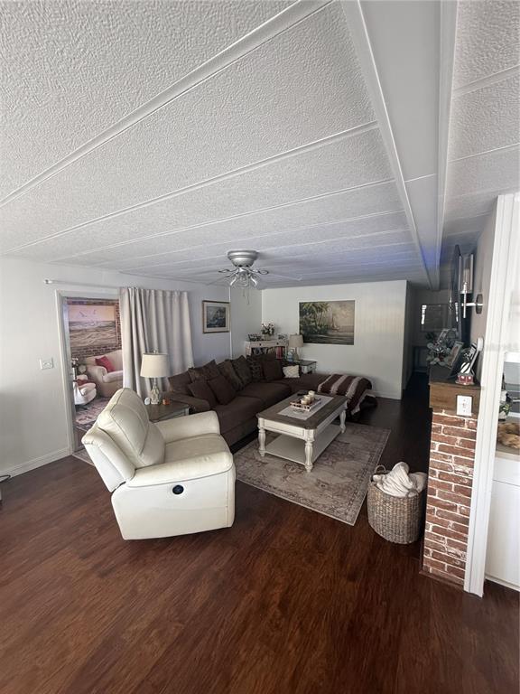 A living room features a brown sectional sofa, a white recliner, and wood-look flooring — 7880 54TH AVENUE N UNIT 125, ST PETERSBURG, FL