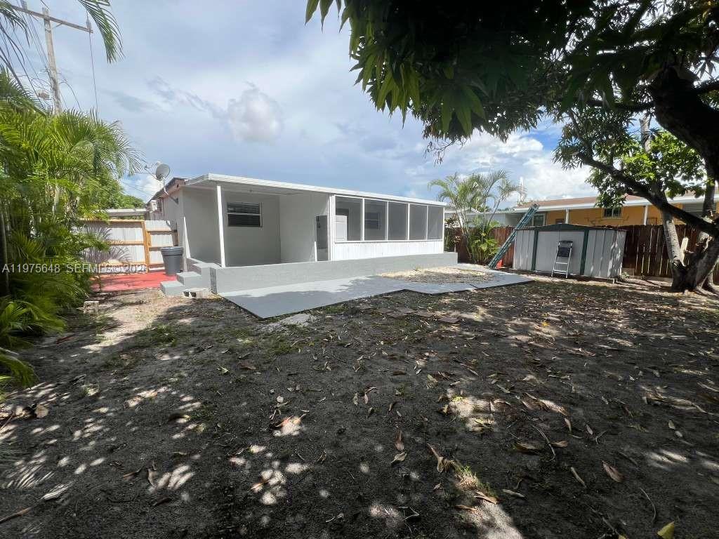 A backyard view of a house with a screened-in patio and a metal shed — 4365 W 1st Ave, Hialeah FL 33012, HIALEAH, FL