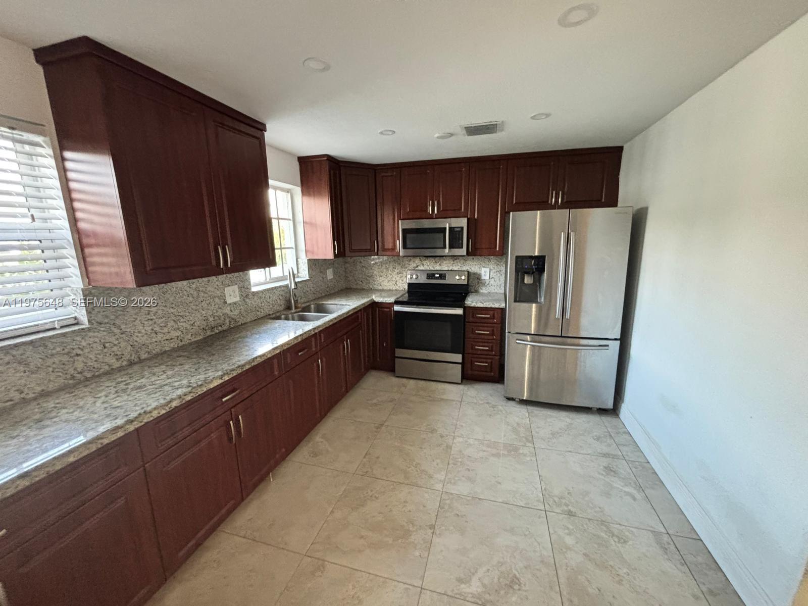A kitchen features dark wood cabinets, granite countertops, stainless steel appliances, and tile flooring — 4365 W 1st Ave, Hialeah FL 33012, HIALEAH, FL