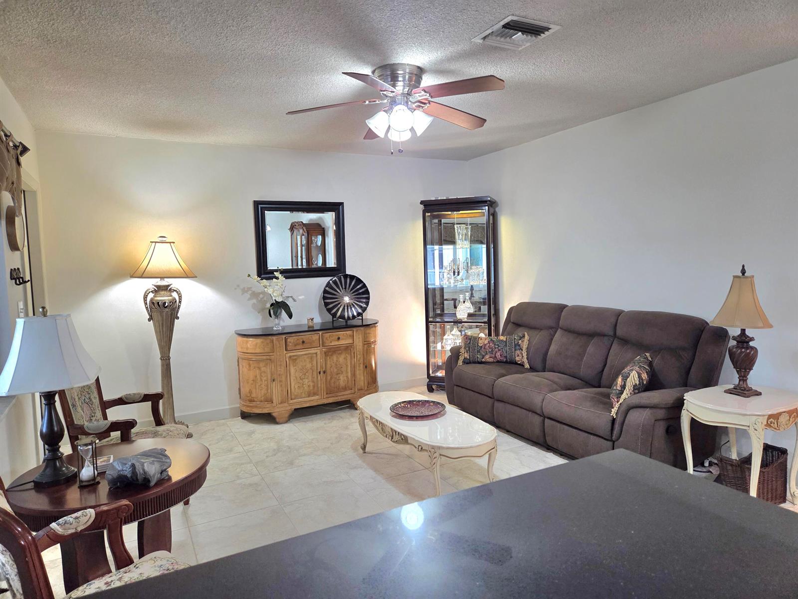A living room features a brown sofa, a wooden sideboard, and a ceiling fan — 2100 NE 38th Street NE # 207, Lighthouse Point FL 33064, LIGHTHOUSE POINT, FL
