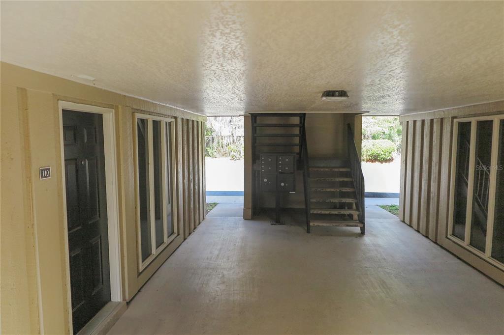 A covered outdoor walkway features a black door, a staircase, and a cluster of mailboxes — 507 NW 39TH DRIVE UNIT 210, GAINESVILLE, FL