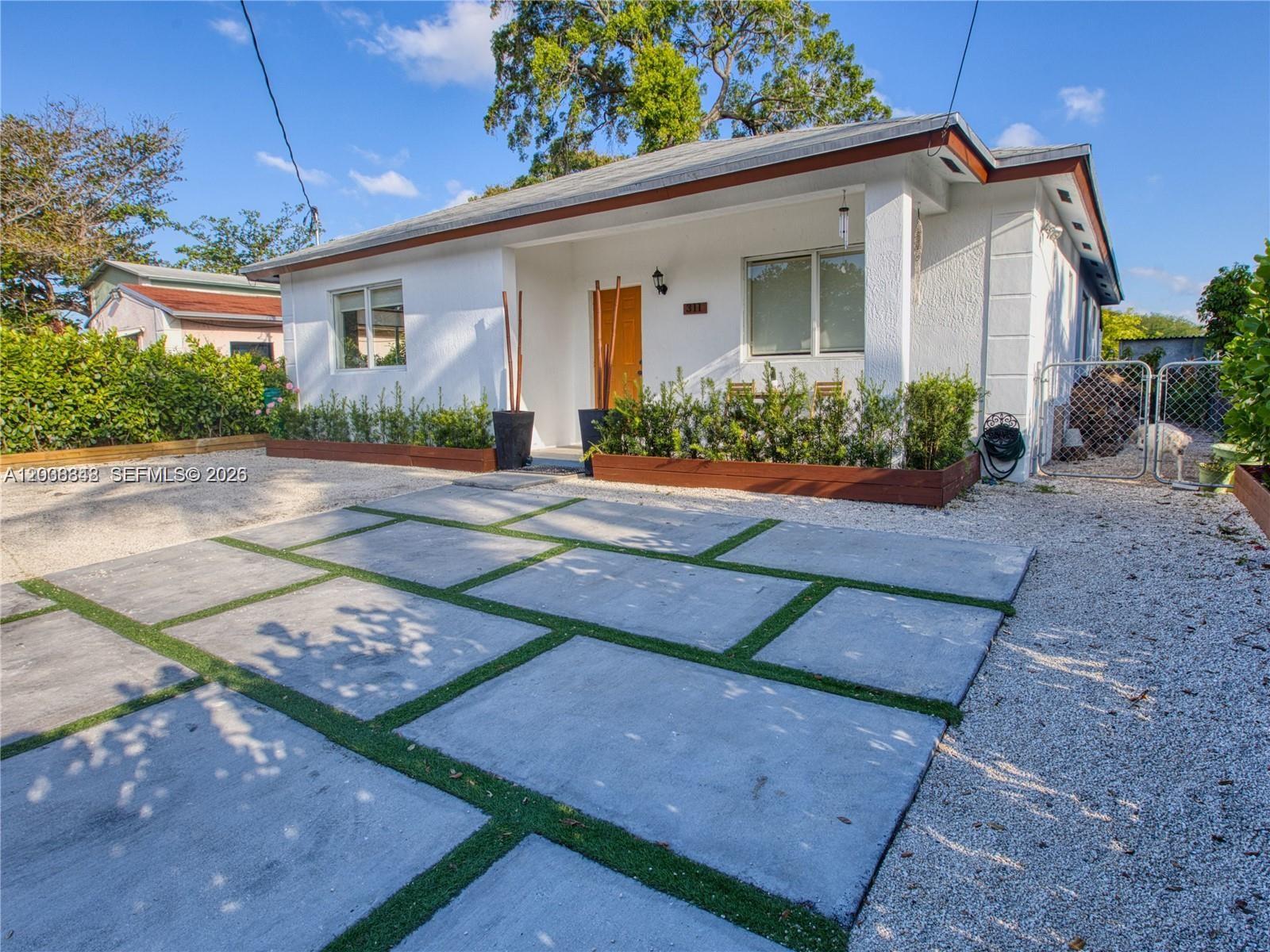 A white house features a concrete paver driveway with grass strips and a front porch — 311 NW 95th St, Miami FL 33150, MIAMI, FL