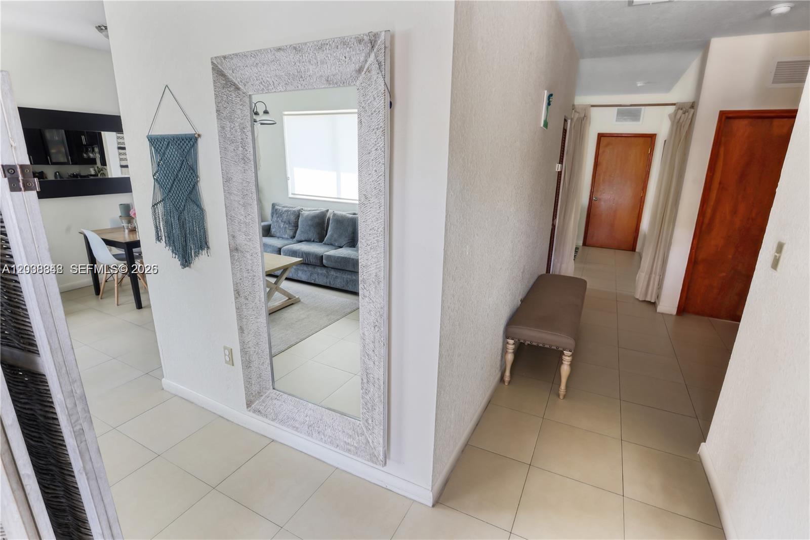 A hallway with a large mirror, a bench, and views into a living and dining area — 311 NW 95th St, Miami FL 33150, MIAMI, FL