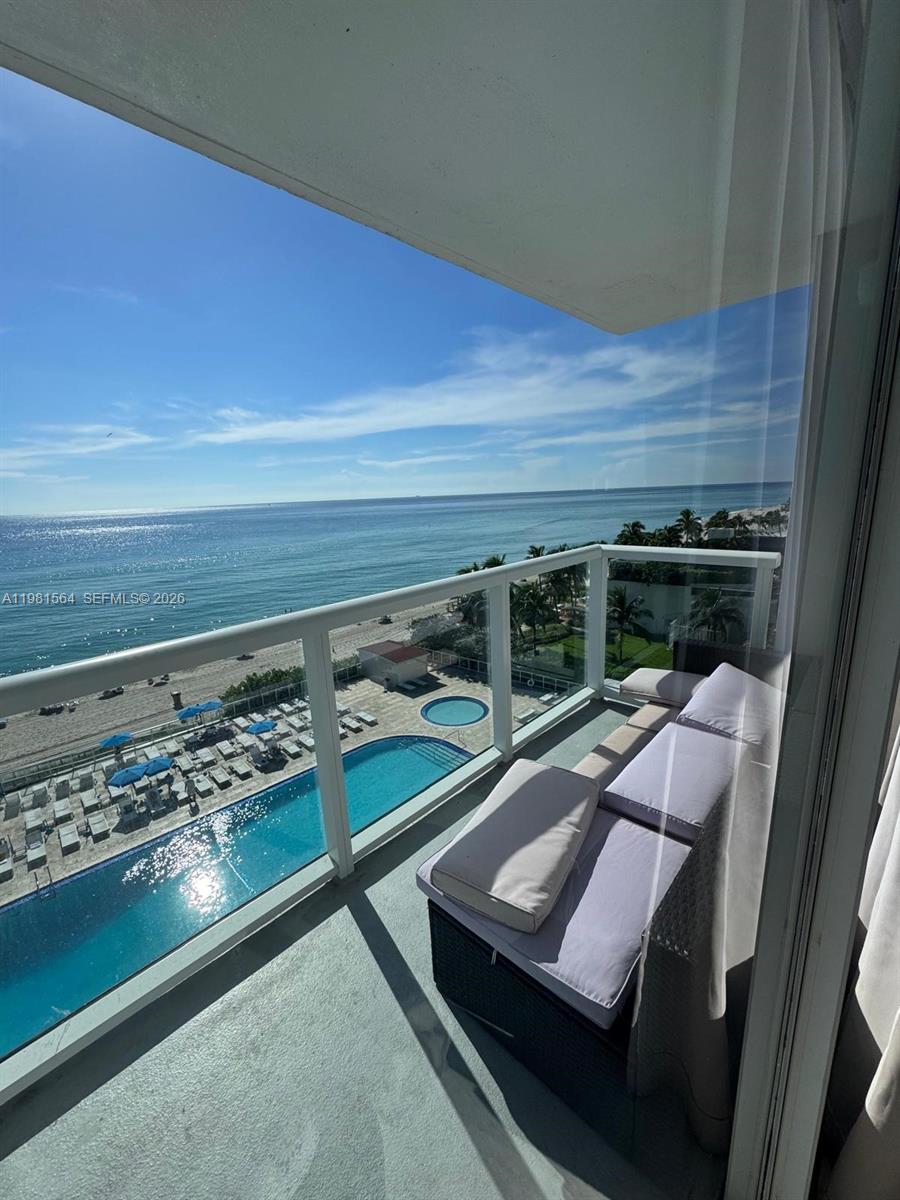A balcony with outdoor seating overlooks a swimming pool, beach, and the ocean — SUNNY ISLES BEACH, FL