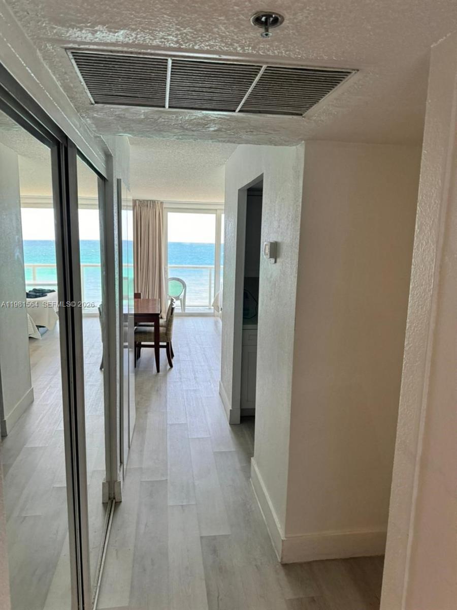 A hallway with mirrored closet doors leads to a dining area overlooking the ocean — SUNNY ISLES BEACH, FL