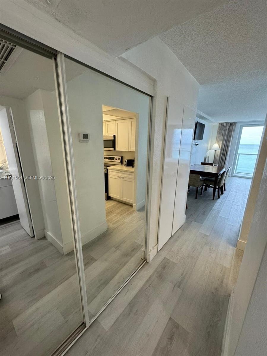 A hallway with mirrored closet doors leads to a kitchen and a dining area — SUNNY ISLES BEACH, FL