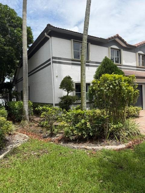 A two-story stucco townhouse features dark trim, palm trees, and landscaped bushes in front — 2440 NW 99th Way, Sunrise FL 33322, SUNRISE, FL
