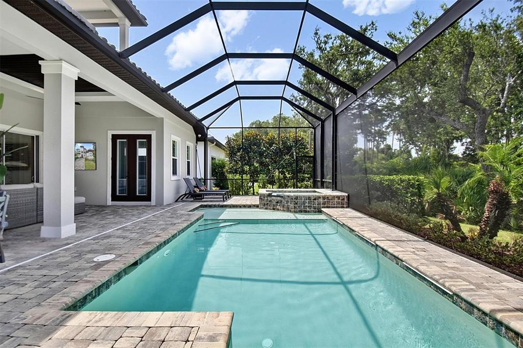A screened-in patio features a rectangular swimming pool, a raised spa, and stone pavers — 23 N RIVERWALK DRIVE, PALM COAST, FL