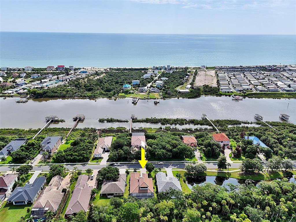 An aerial view shows a residential neighborhood with a house highlighted by a yellow arrow — 23 N RIVERWALK DRIVE, PALM COAST, FL