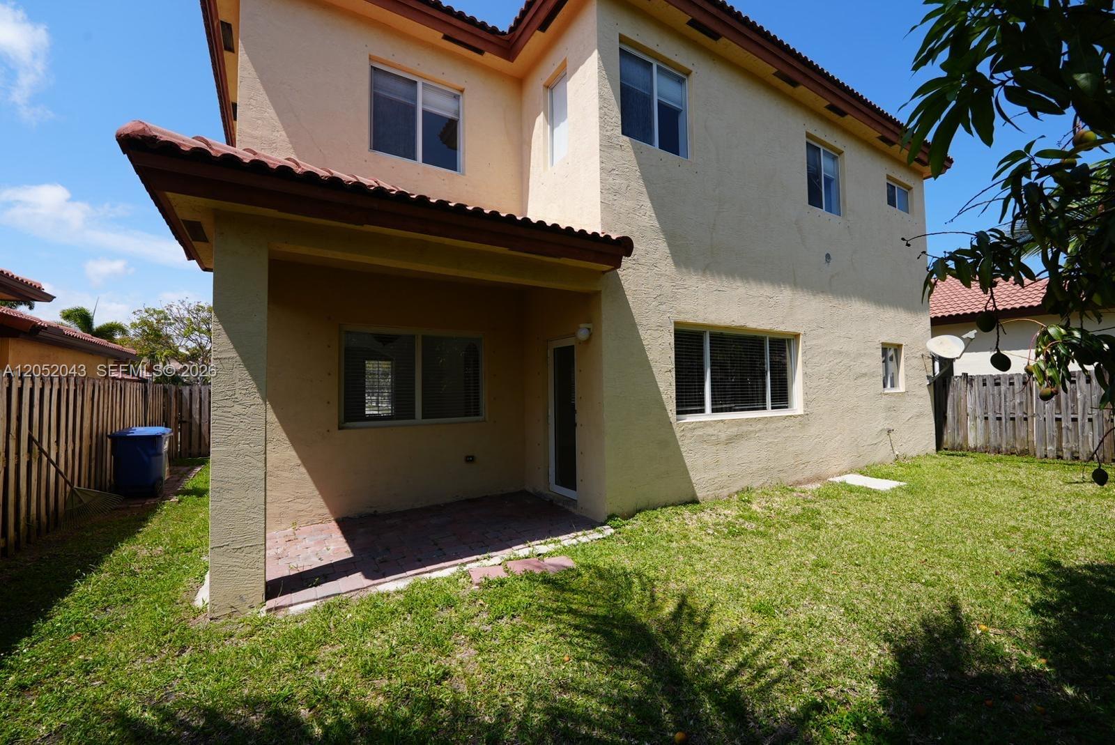 The exterior of a two-story stucco house features a covered patio and a grassy backyard — 8836 SW 221 Terr, Miami FL 33190, MIAMI, FL