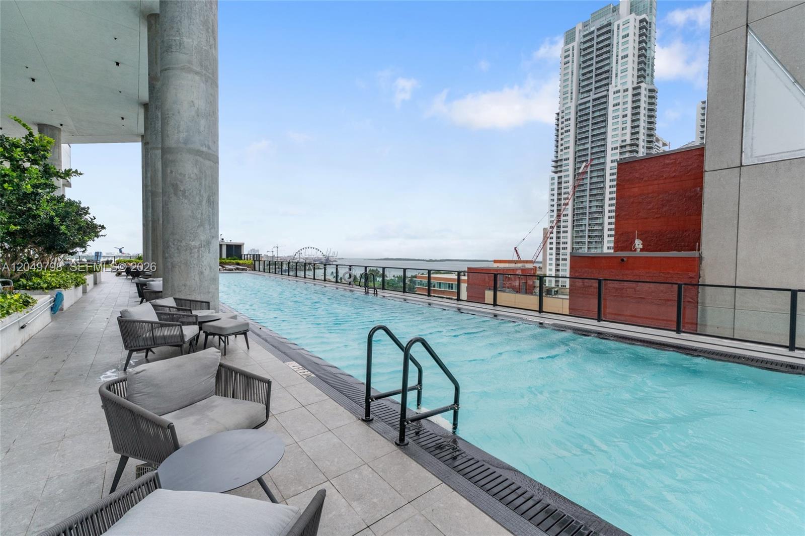 An outdoor rooftop infinity pool overlooks a city skyline and a body of water — 398 NE 5th St # 4719, Miami FL 33132, MIAMI, FL