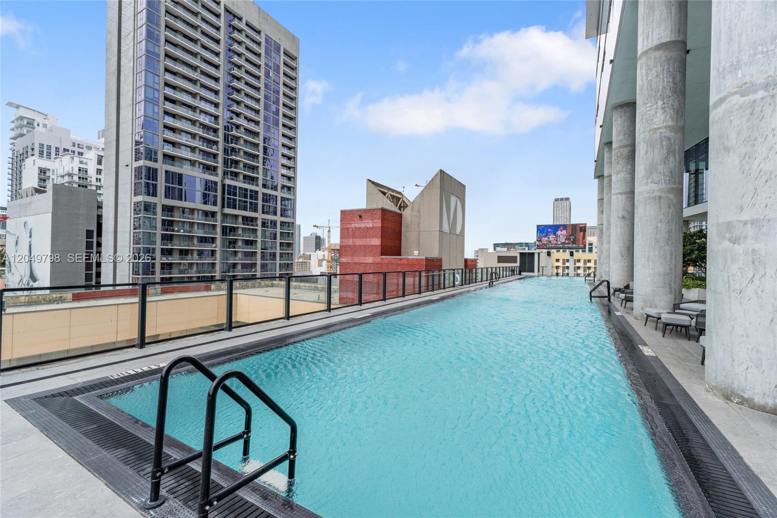 An outdoor rooftop swimming pool with a glass railing overlooks a city skyline — 398 NE 5th St # 4719, Miami FL 33132, MIAMI, FL