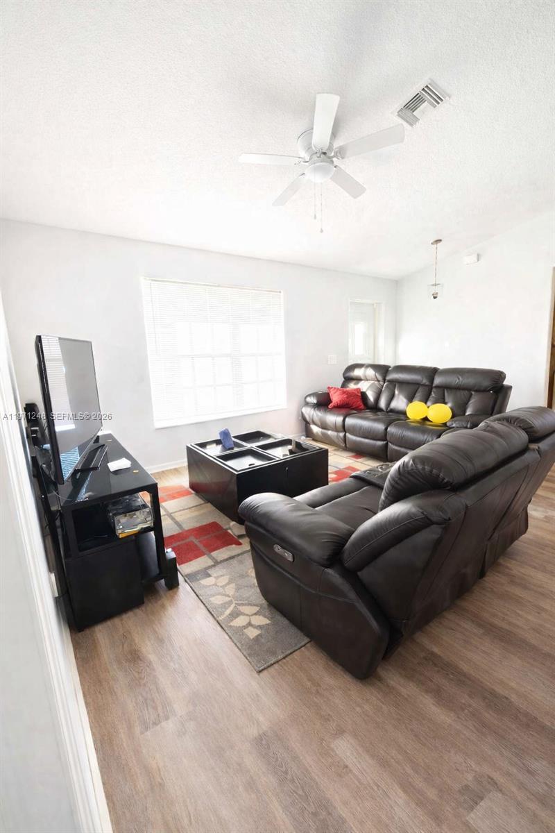 A living room features dark leather sofas, a black coffee table, and a television stand — 1518 SENIOR CT, Lehigh Acres FL 33971, LEHIGH ACRES, FL