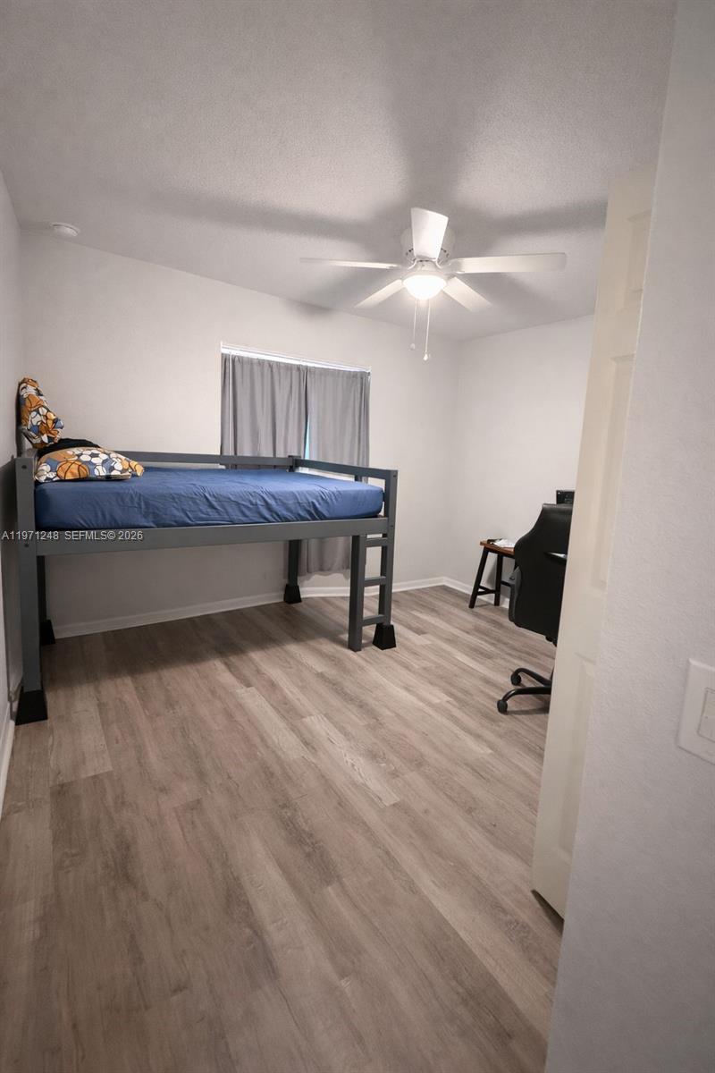 A bedroom features a loft bed, wood-look flooring, a ceiling fan, and a desk area — 1518 SENIOR CT, Lehigh Acres FL 33971, LEHIGH ACRES, FL