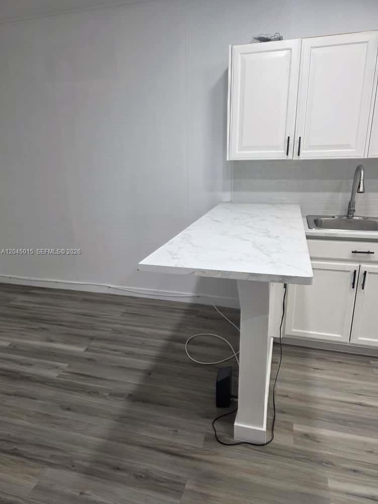 A kitchen features white cabinets, a marble-patterned breakfast bar, and gray wood-look flooring — 23 Miami Gardens Rd # 3, West Park FL 33023, WEST PARK, FL