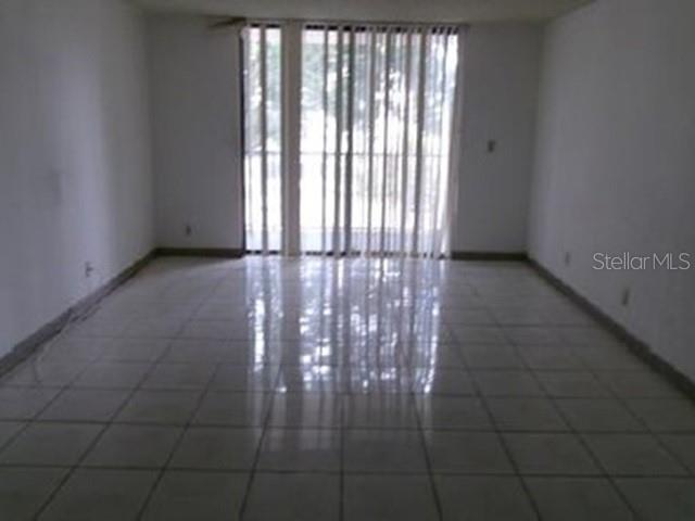 An empty room features white walls, light-colored tile flooring, and a large sliding glass door — 6190 WOODLANDS BOULEVARD UNIT 309, TAMARAC, FL