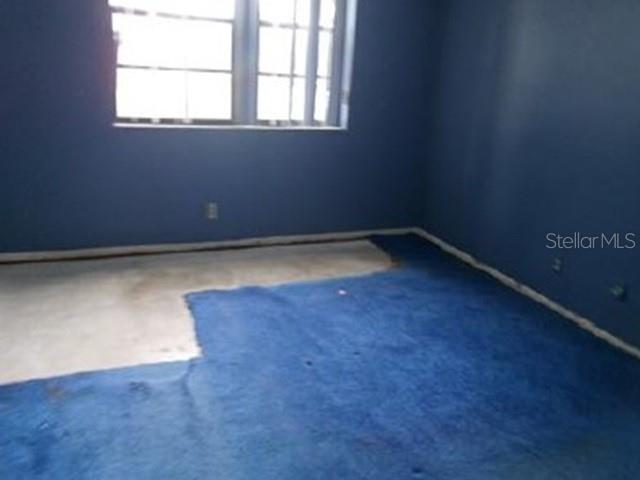 An empty bedroom with blue walls and a partially carpeted concrete floor — 6190 WOODLANDS BOULEVARD UNIT 309, TAMARAC, FL