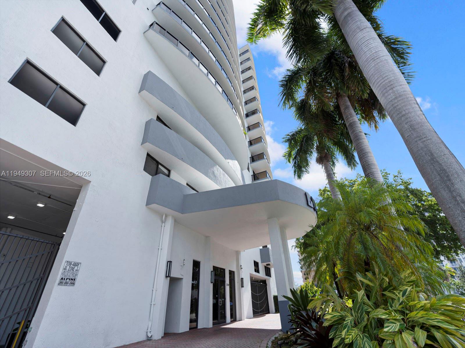 A low-angle exterior view of a white high-rise building with balconies and palm trees — 2301 SW 27th Ave # 1403, Miami FL 33145, MIAMI, FL