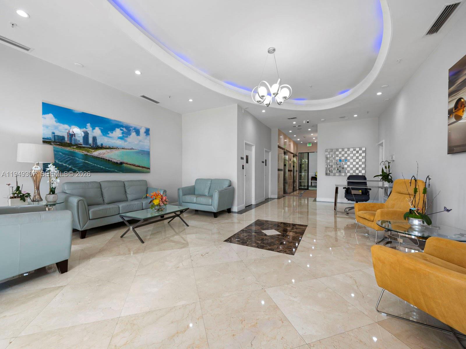 A modern lobby features light-colored tile floors, blue and yellow seating, and a circular ceiling — 2301 SW 27th Ave # 1403, Miami FL 33145, MIAMI, FL