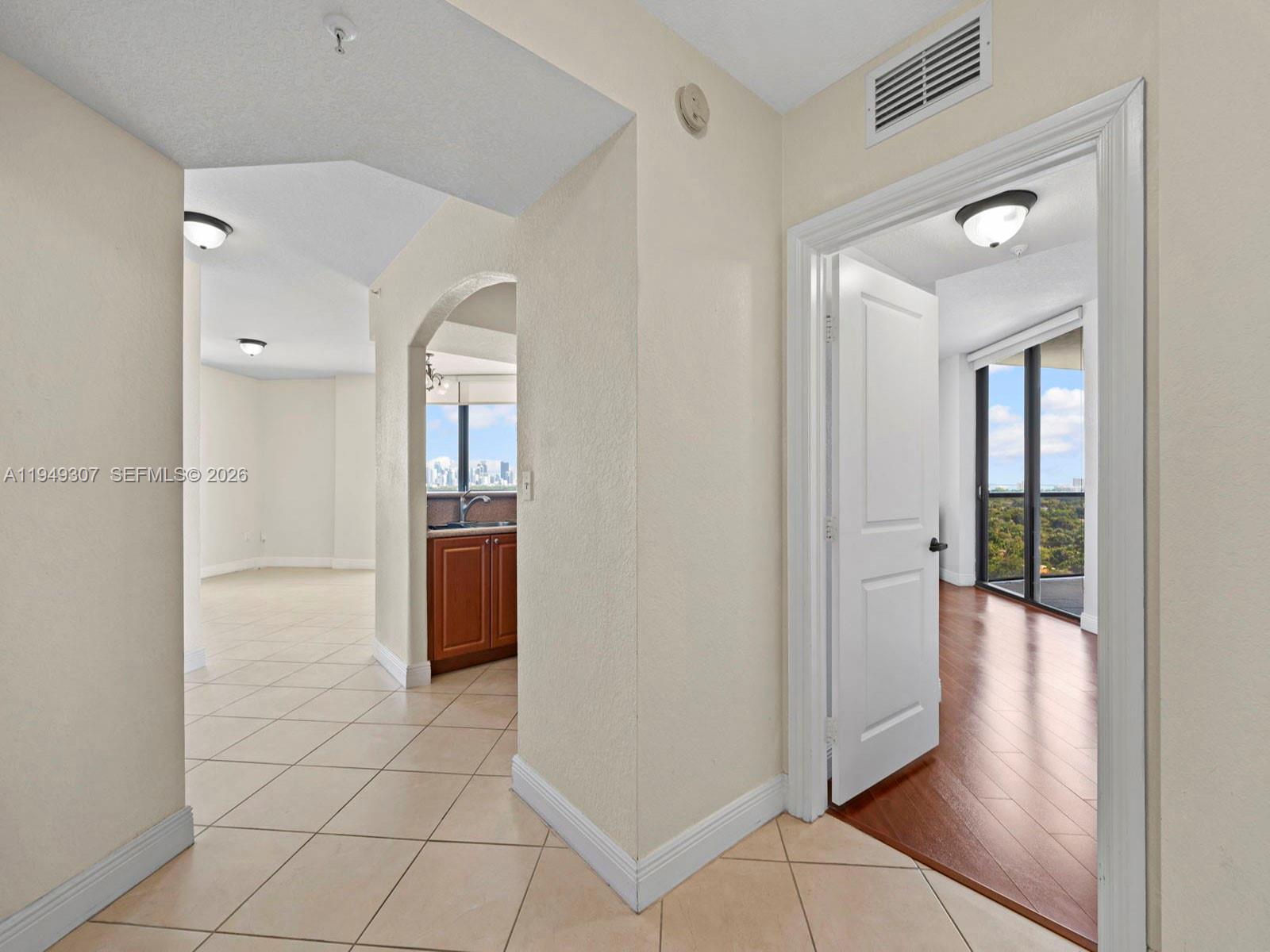 A hallway with tile flooring leads to a kitchen and a room with wood floors — 2301 SW 27th Ave # 1403, Miami FL 33145, MIAMI, FL