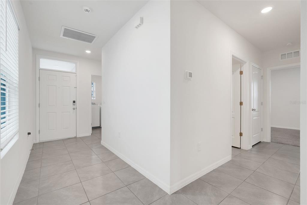 An entryway with gray tile flooring, white walls, and a white front door — 3881 BRANT PLACE, LEESBURG, FL