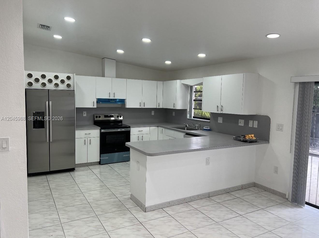 A kitchen features white cabinets, gray countertops, stainless steel appliances, and light-colored tiled flooring — 11461 SW 193rd St # 0, Miami FL 33157, MIAMI, FL