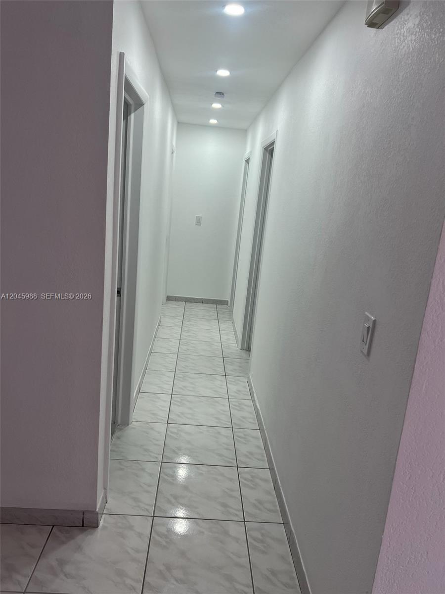 A narrow hallway features white walls, recessed ceiling lights, and light-colored tiled flooring — 11461 SW 193rd St # 0, Miami FL 33157, MIAMI, FL