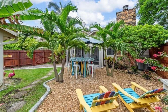 A backyard patio features a stone chimney, palm trees, a dining set, and two wooden chairs — 1960 Derby Trail, Wellington FL 33414, WELLINGTON, FL
