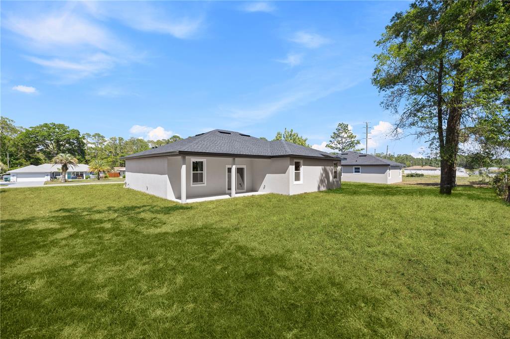 The rear exterior of a single-story gray house with a lawn and a covered patio — 44 W GULFSTREAM PLACE, CITRUS SPRINGS, FL