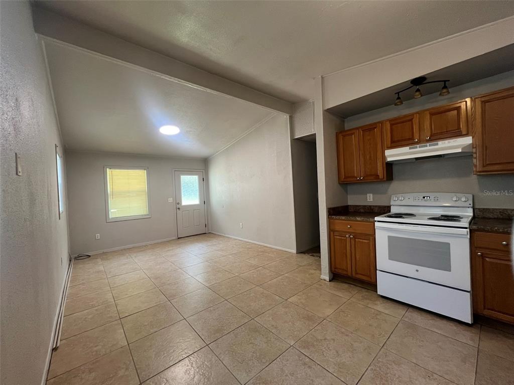 A kitchen with wood cabinets and tile flooring opens into a living area with tile — 13711 NW 158TH PLACE, ALACHUA, FL