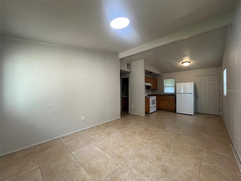 An open-concept kitchen and dining area features light tile flooring and wood cabinetry — 13711 NW 158TH PLACE, ALACHUA, FL