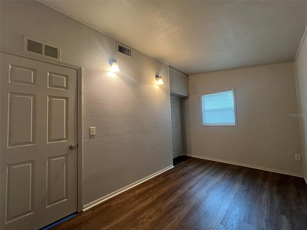 An interior room features light gray walls, wood-look flooring, two wall-mounted lights, and two doors — 13711 NW 158TH PLACE, ALACHUA, FL