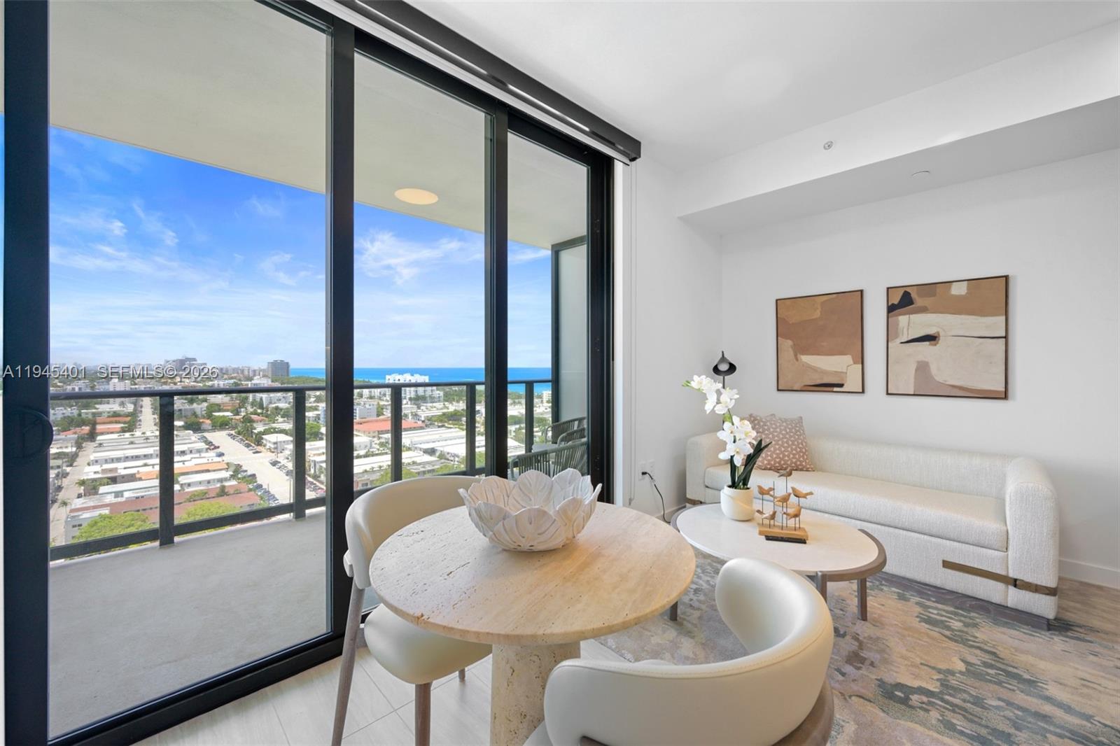 A modern living and dining area features floor-to-ceiling windows with an ocean view — 580 72nd St # 1603, Miami Beach FL 33141, MIAMI BEACH, FL