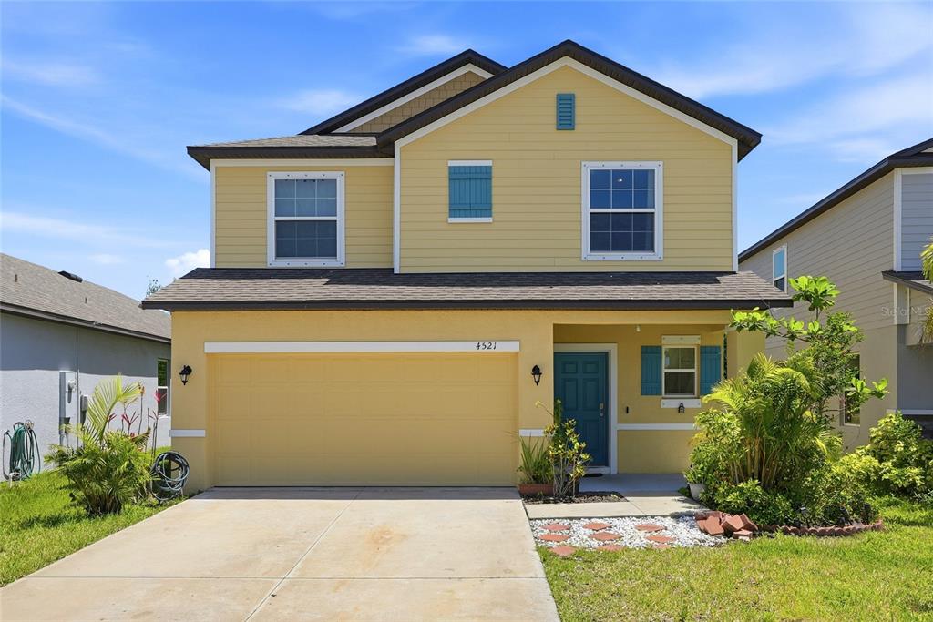 A two-story yellow house with a two-car garage and a blue front door — 4521 REISSWOOD LOOP, PALMETTO, FL