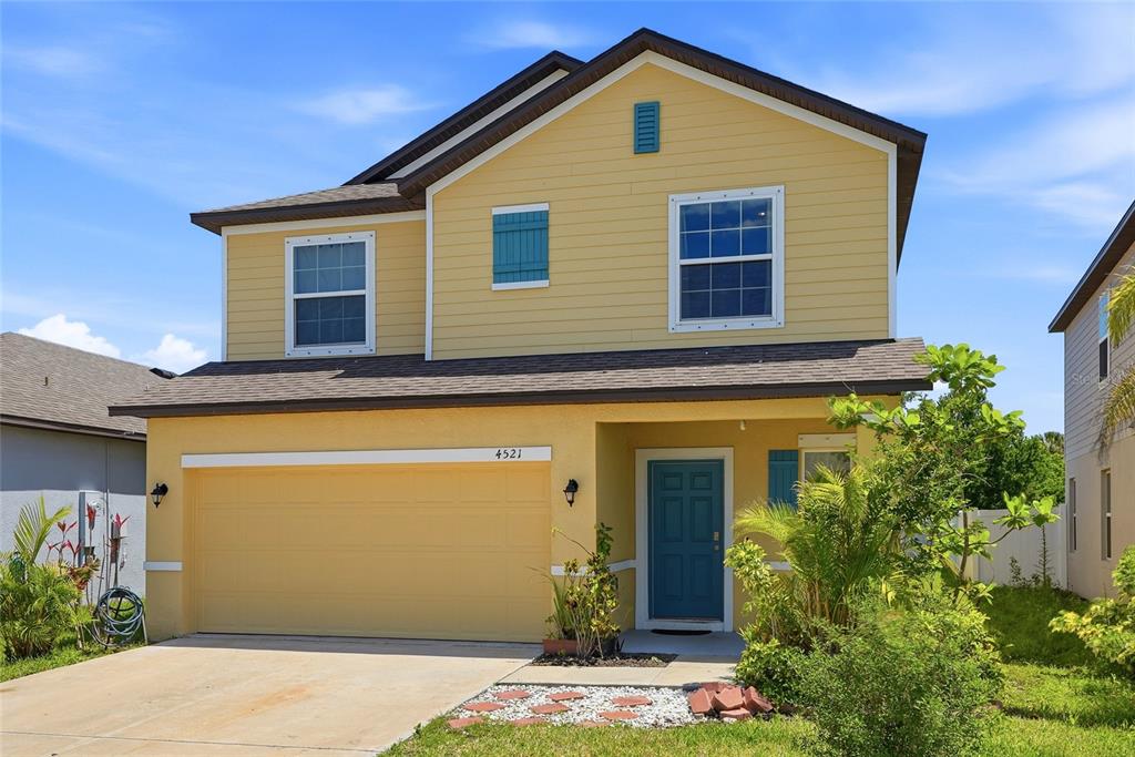 A two-story yellow house with a two-car garage and a blue front door — 4521 REISSWOOD LOOP, PALMETTO, FL
