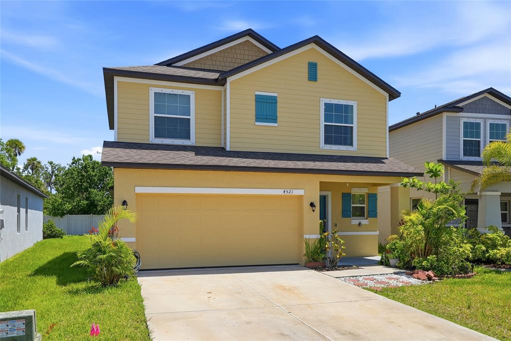 A two-story yellow house with a two-car garage and a concrete driveway — 4521 REISSWOOD LOOP, PALMETTO, FL