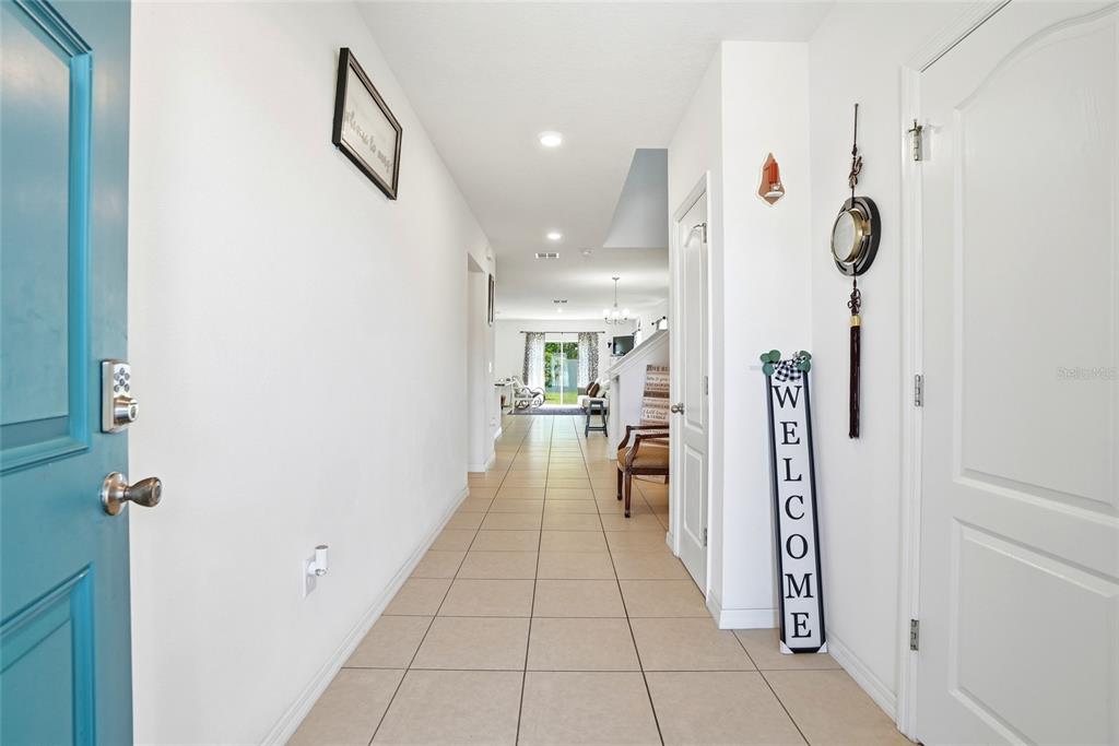 A bright entryway with tiled floors leads down a hallway toward an open living area — 4521 REISSWOOD LOOP, PALMETTO, FL
