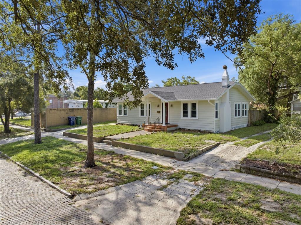 A single-story house with light siding, a red front door, and a brick porch — 106 W COMANCHE AVENUE, TAMPA, FL