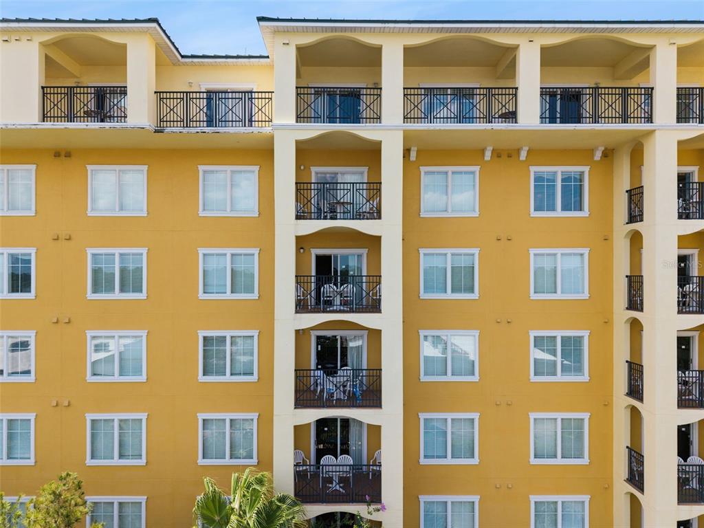 An exterior view of a multi-story yellow apartment building with balconies and white-trimmed windows — 8100 POINCIANA BOULEVARD UNIT 2609, ORLANDO, FL