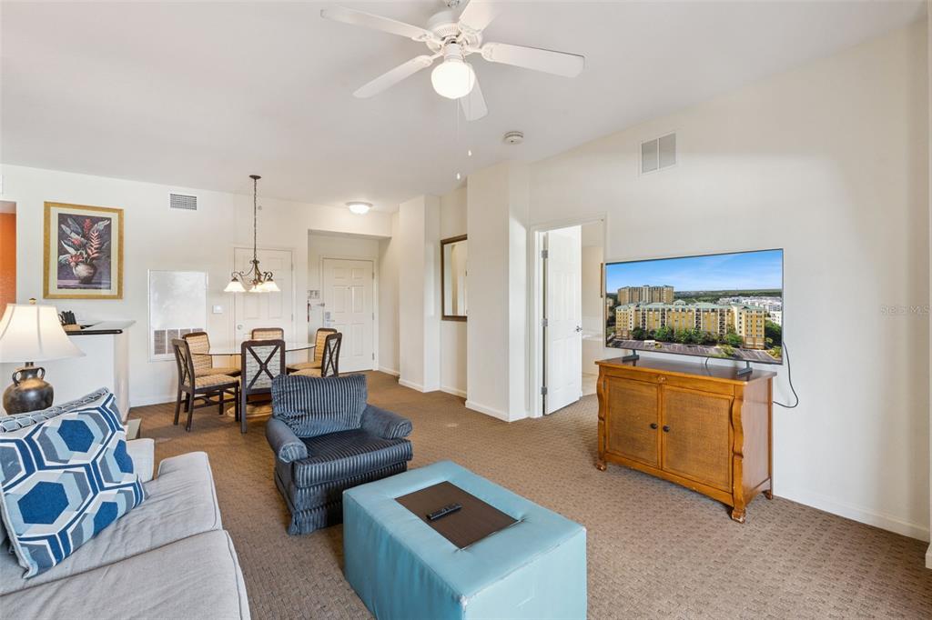 A living room with a television, a dining area, and carpeted flooring — 8100 POINCIANA BOULEVARD UNIT 2609, ORLANDO, FL