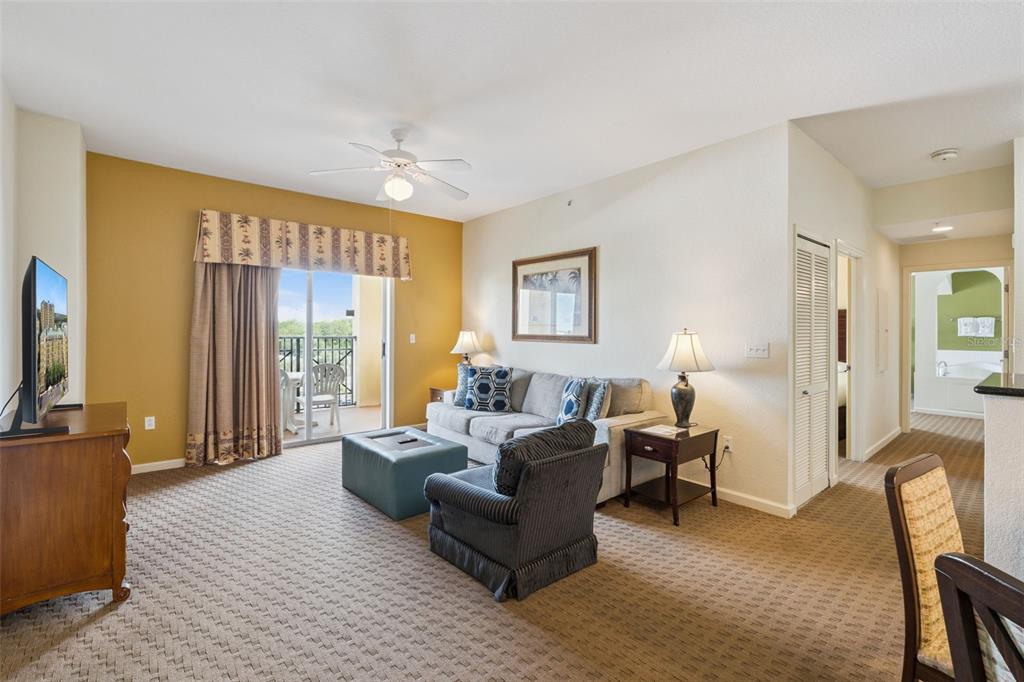A living room features a sofa, armchair, ottoman, television, and a sliding door to a balcony — 8100 POINCIANA BOULEVARD UNIT 2609, ORLANDO, FL