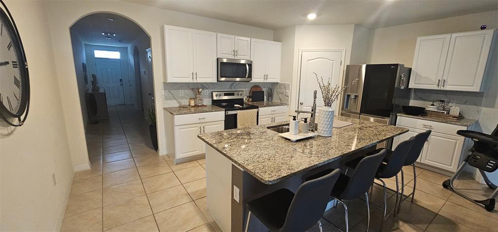 A kitchen with white cabinets, granite countertops, a central island, and stainless steel appliances — 1575 BARBERRY DRIVE, KISSIMMEE, FL