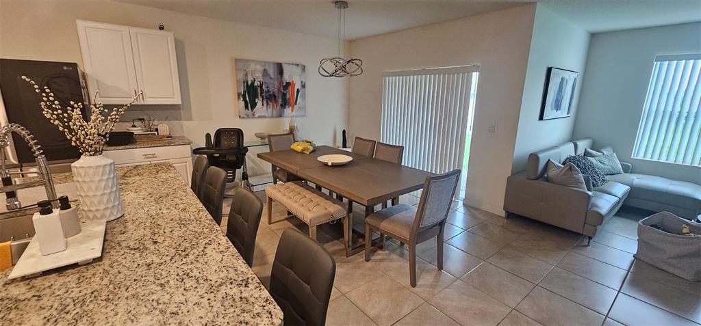 An open-concept kitchen, dining area, and living room featuring tile floors and granite countertops — 1575 BARBERRY DRIVE, KISSIMMEE, FL