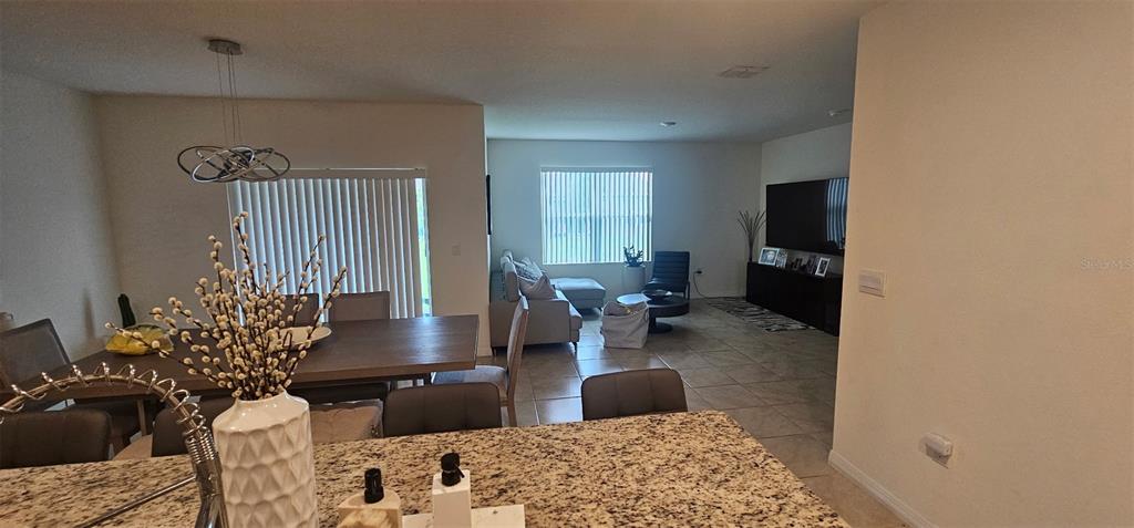 An open-concept living and dining area features tile flooring, a granite kitchen island, and neutral walls — 1575 BARBERRY DRIVE, KISSIMMEE, FL
