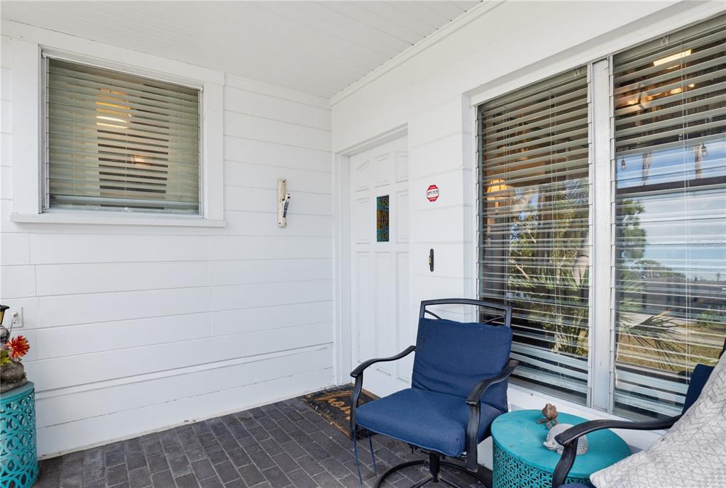 A covered porch features white horizontal siding, a dark brick floor, and a front door — 2719 FORT WORTH STREET, SARASOTA, FL