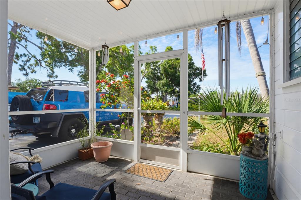 A screened-in porch features a brick floor, a screen door, and views of a parked vehicle — 2719 FORT WORTH STREET, SARASOTA, FL