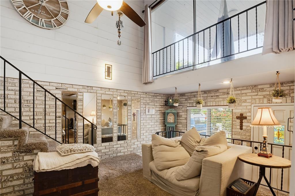 A living room features a high ceiling, white shiplap walls, brick accents, and a loft balcony — 2719 FORT WORTH STREET, SARASOTA, FL