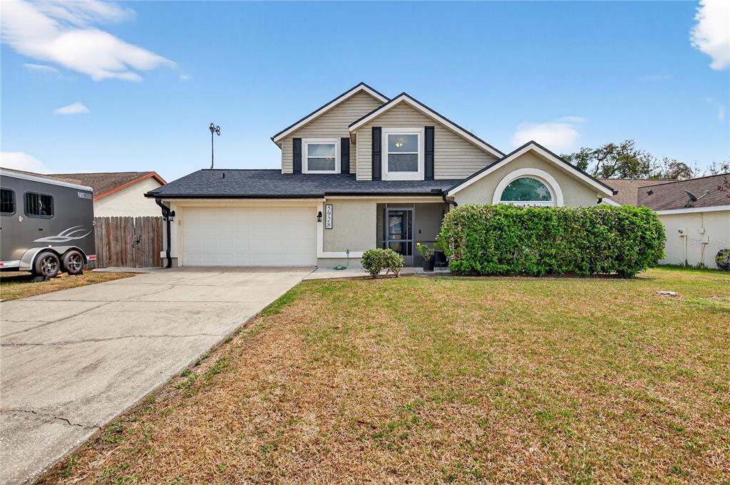 A two-story house with a beige exterior, a two-car garage, and a front lawn — 5928 BOGGS FORD ROAD, PORT ORANGE, FL