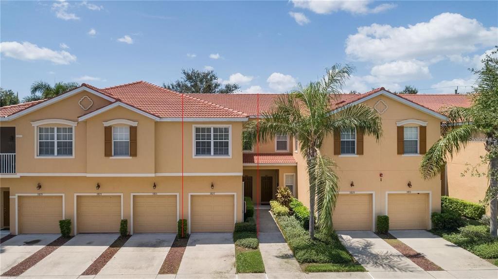 A row of two-story townhomes with tan stucco walls, tile roofs, and attached garages — 3827 PARKRIDGE CIRCLE UNIT 1-102, SARASOTA, FL